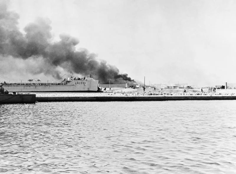 Tank landing ship HMS BUTTRESS disembarks troops and vehicles on the landing beach at the fishing harbour in Port Said