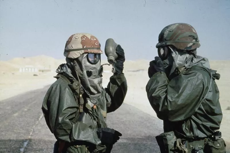 The Gulf War 1991: Two United States soldiers drinking from water bottles whilst wearing NBC [Nuclear Biological and Chemical] protective outfits