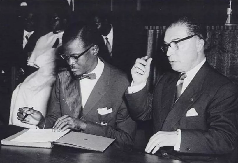 Congolese Prime Minister Patrice Lumumba signs the document granting independence to the Congo next to Belgian Prime Minister Gaston Eyskens