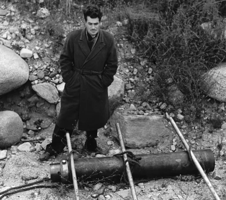 John Whiteside "Jack" Parsons standing above a Jet-Assisted Take Off canister at JPL's test site in the Arroyo Seco, Los Angeles County. 4 June 1943