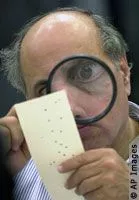 Judge Robert Rosenberg closely examines a Florida punch card ballot from the 2000 US Presidential election for signs of a hanging chad.