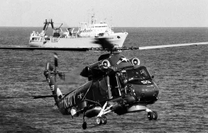 An SH-2F LAMPS helicopter equipped with magnetic anomaly detection gear hovers over the water as a Soviet ship shadows salvage operations for downed Korean Air Lines Flight 007 (KAL 007). The commercial jet was shot down by Soviet aircraft over Sakhalin Island in the Sea of Japan on August 30, 1983.