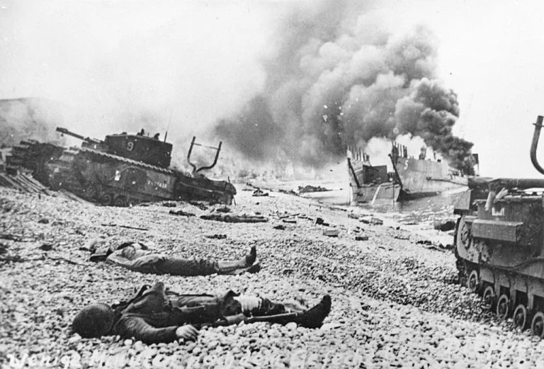 A burning LCT (Landing Craft, Tank) TLC5 No. 121 near the beach after the raid by allied (mostly Canadian) air, naval and land forces on german defences. Churchill tanks and bodies of allied servicemen are pictured on the beach. The tank at left is one from 9 Troop 14th Army Tank Battalion (The Calgary Regiment (Tank)) which was transported by TLC5.