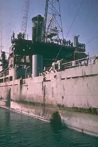 USS Liberty (AGTR-5) at La Valletta, Malta, after arriving for repair of damages received when she was attacked by Israeli forces off the Sinai Peninsula on 8 June 1967. She arrived at Malta on 14 June. Note torpedo hole in her hull side, forward of the superstructure