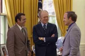 Photograph of President Gerald R. Ford chatting with Chief of Staff Donald Rumsfeld and Rumsfeld’s Assistant Richard Cheney in the Oval Office. 28 April 1975