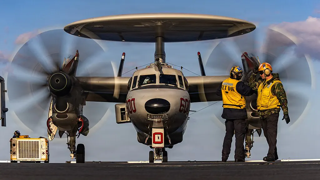 U.S. Navy Sailors signal to an E-2D Hawkeye aircraft, attached to Airborne Command and Control Squadron 124, as it taxis on the flight deck of world's largest aircraft carrier, USS Gerald R. Ford (CVN 78), in support of Operation Epic Fury, Feb. 28, 2026
